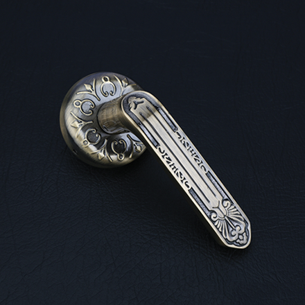 Sleek brass and dark textured lever door handle on a round rose