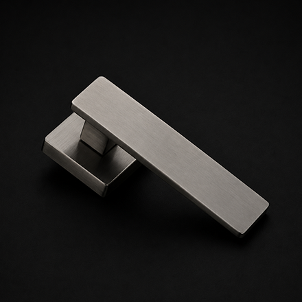 Modern black and brass rectangular lever door handle on a round rose