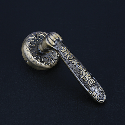 Elegant brass and dark textured lever door handle on a round rose